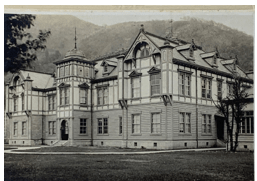 明治時代の西洋風建築の小坂鉱山事務所の外観。重厚なデザインが特徴で、山々を背景にしている。